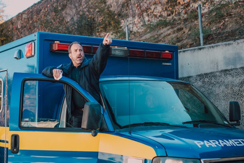 Paramedic pointing and directing from a parked ambulance during an emergency situation.
